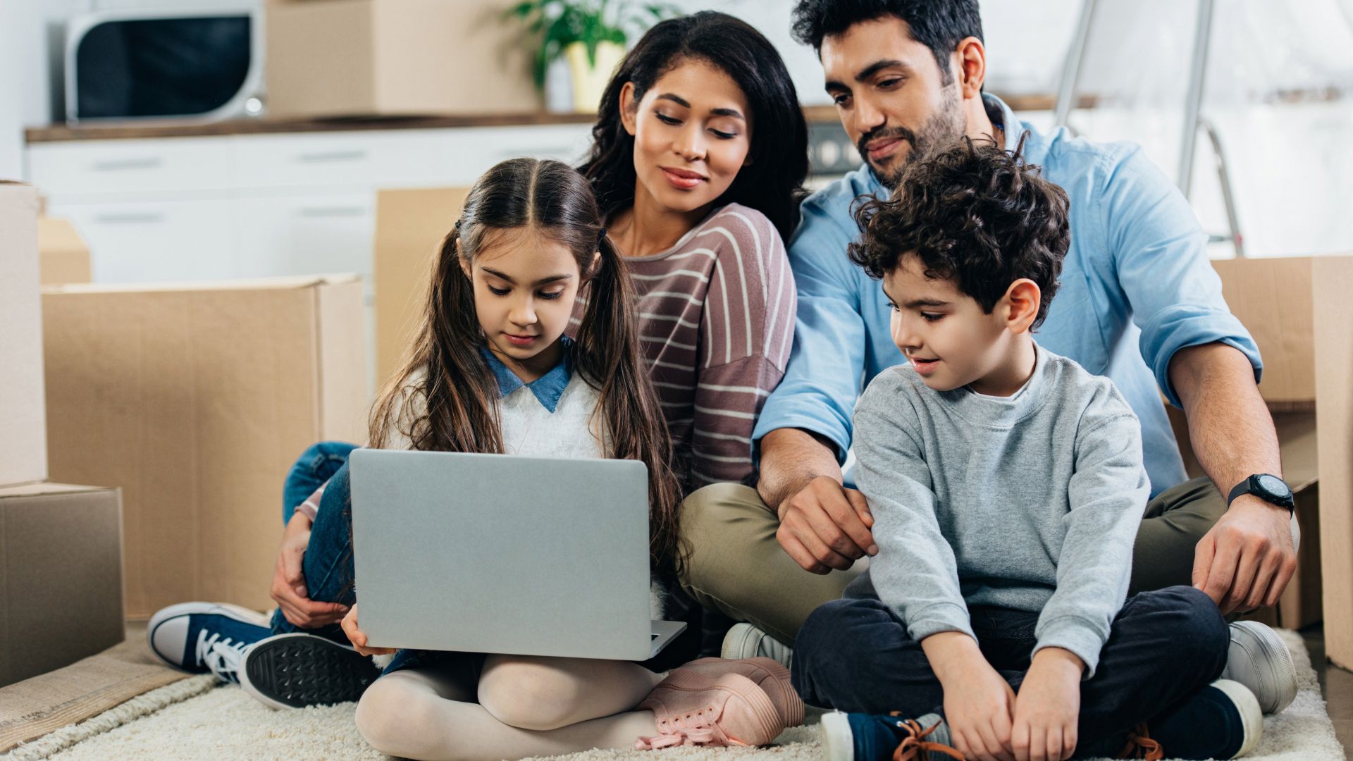 A family photo consisting of father, mother, daughter, and son gathered in the living room while looking at the laptop as targeted content marketing.